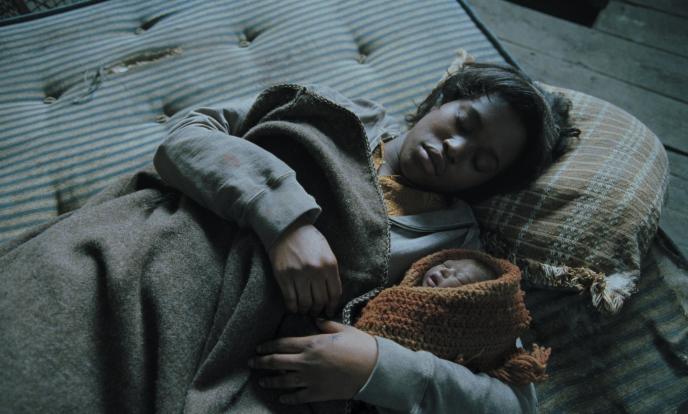 mother and baby from children of men laying down on a mattress