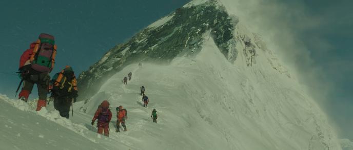 back view of twelve hikers in full hiking gear spread out across the top of a snowy mount everest
