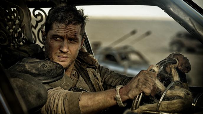 close up of tom hardy as mad max in the driver's seat of a car gazing to the left
