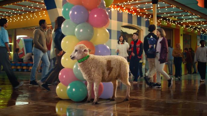 A sheep at a carnival by a pillow arch with a lightning bolt shape in its wool