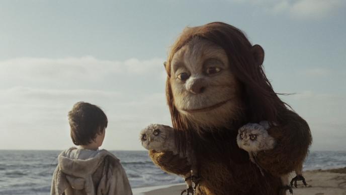 back view of max facing k.w. monster from where the wild things are. they are at a sandy beach and the sea is behind them