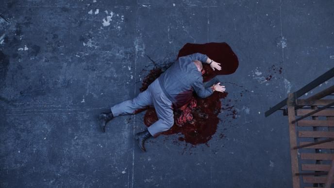 A man lays sprawled out on the concrete in a pool of blood