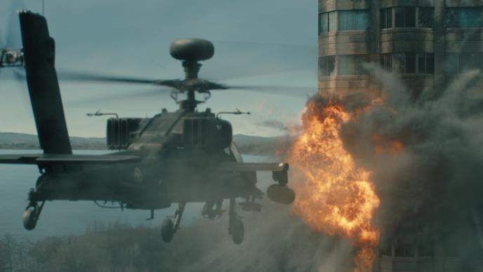 A helicopter shooting a rocket towards a tower block. There is an explosion happening as the rocket hits the building.
