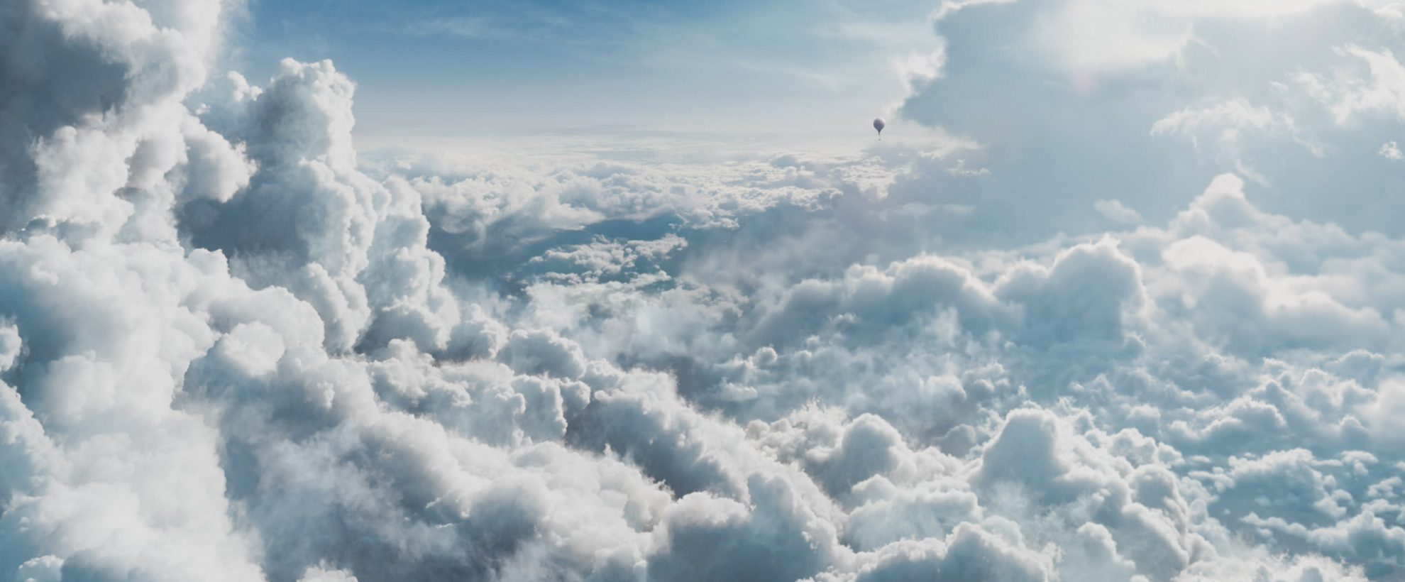 A vast sky above the clouds, with a tiny hot air balloon in the background