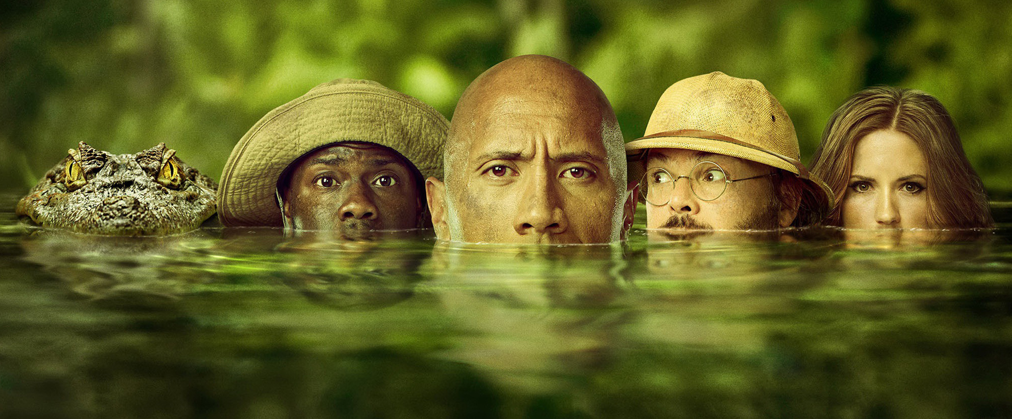 Dwayne Johnson, Kevin Hart, Jack Black, and Karen Gillan with their faces half submerged into a jungle river, on the far left next to Kevin is a crocodile 