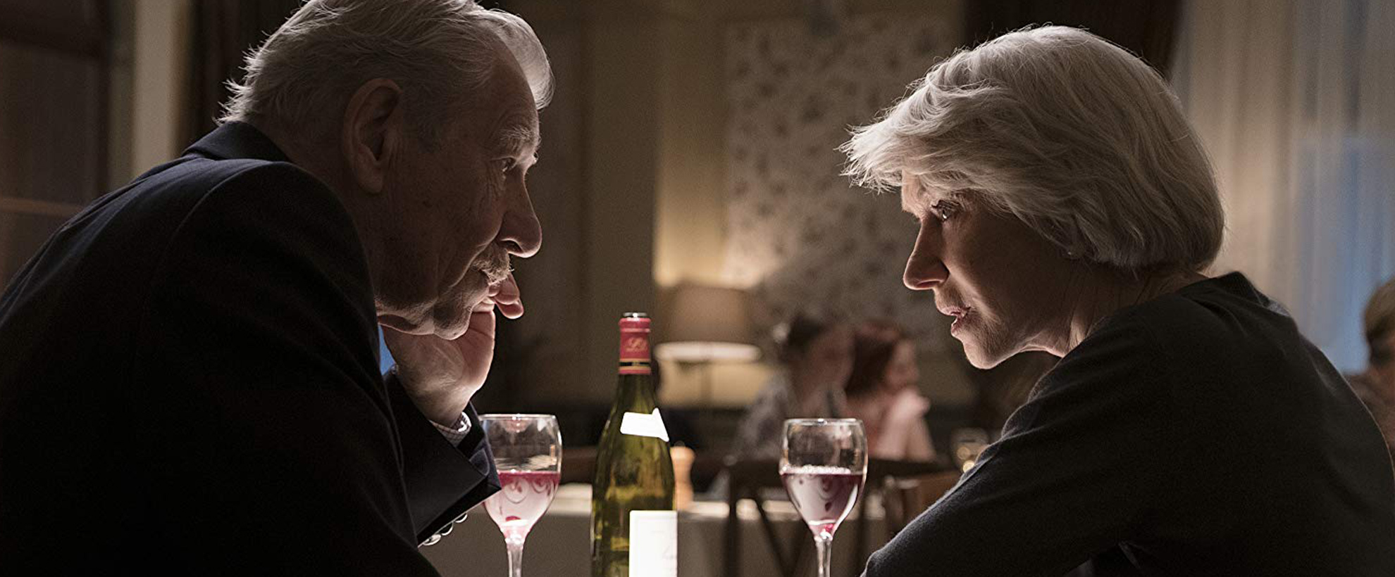 Ian McKellen and Helen Mirren sit at a table in a restaurant, talking intently