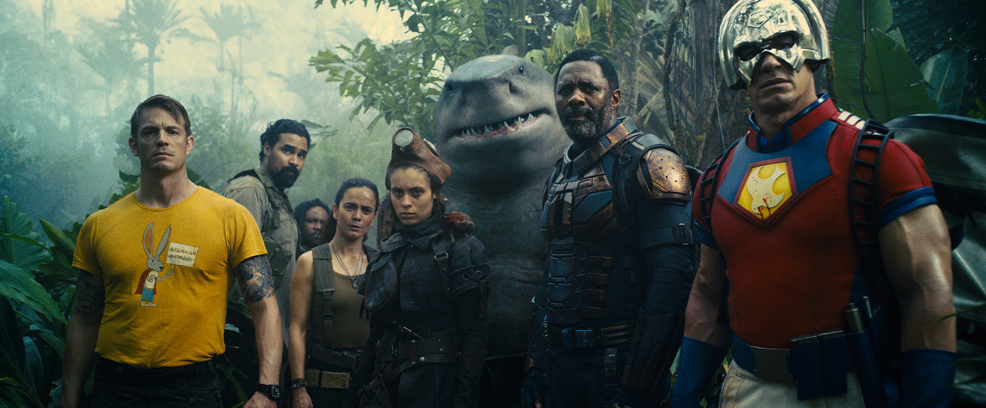 The ensemble cast of the Suicide Squad, standing in a forest, all staring down the camera