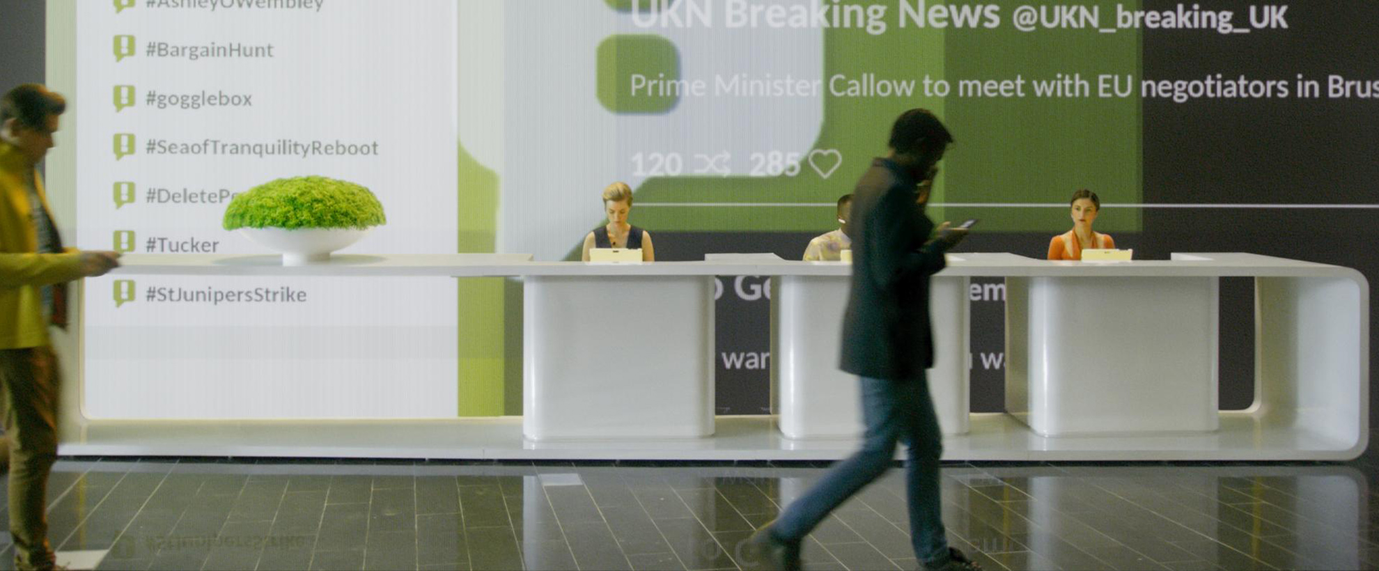 A man walks across a lobby with projections of social media updates