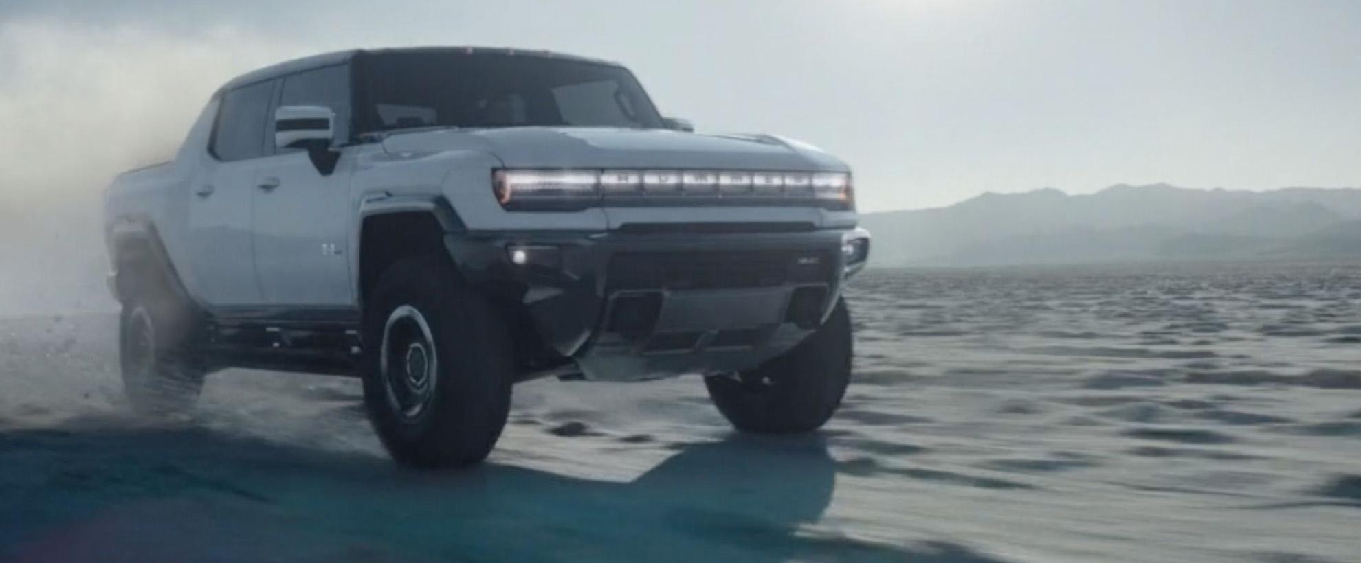 A white Hummer vehicle drives over an icy landscape.