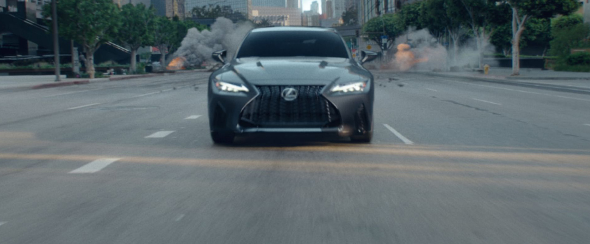 A car is driving towards the camera down a city street with explosions in the background.