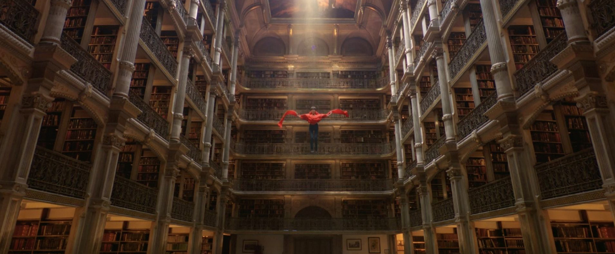 A boy floating down from the ceiling of a large columned room. There is light spilling from a hole in the ceiling.