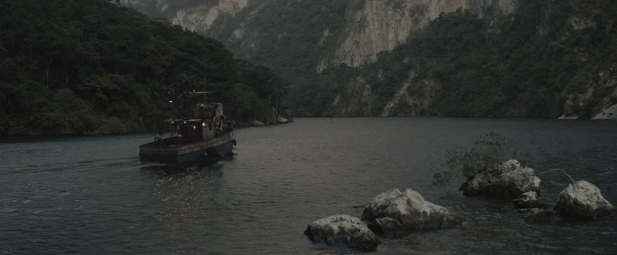 A small fishing boat on a lake towards a mountain