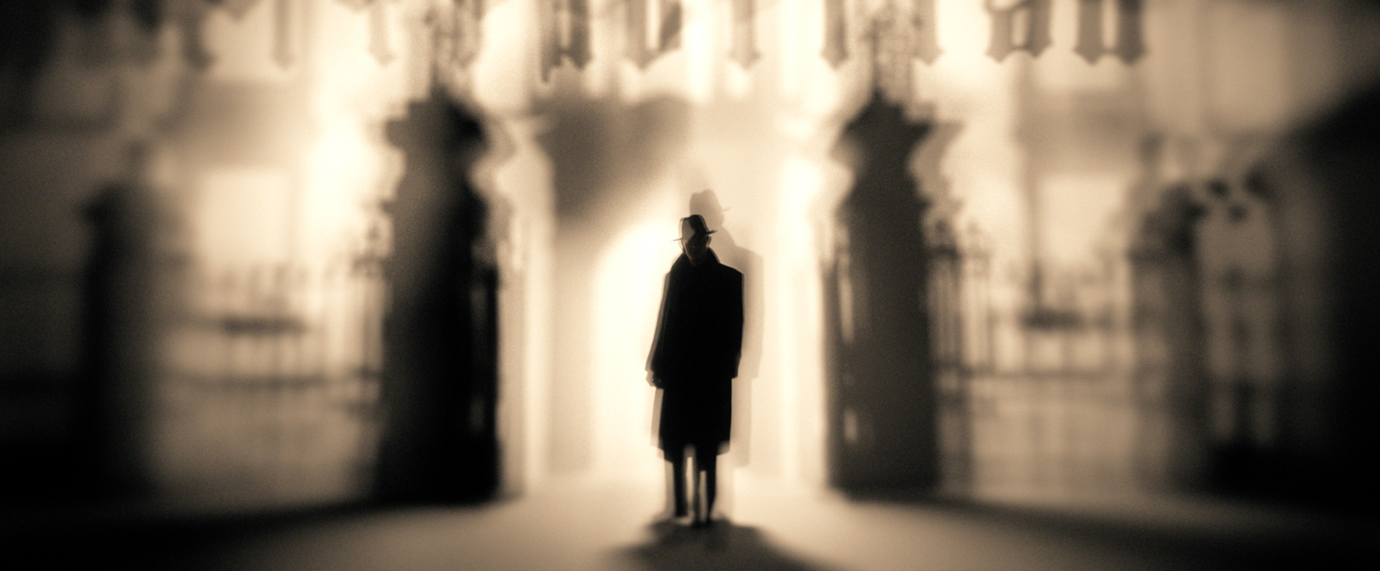 A shot from the SS-GB Titles. A sepia tone background with a fuzzy outline of black gates, with a man stood between the two pillars