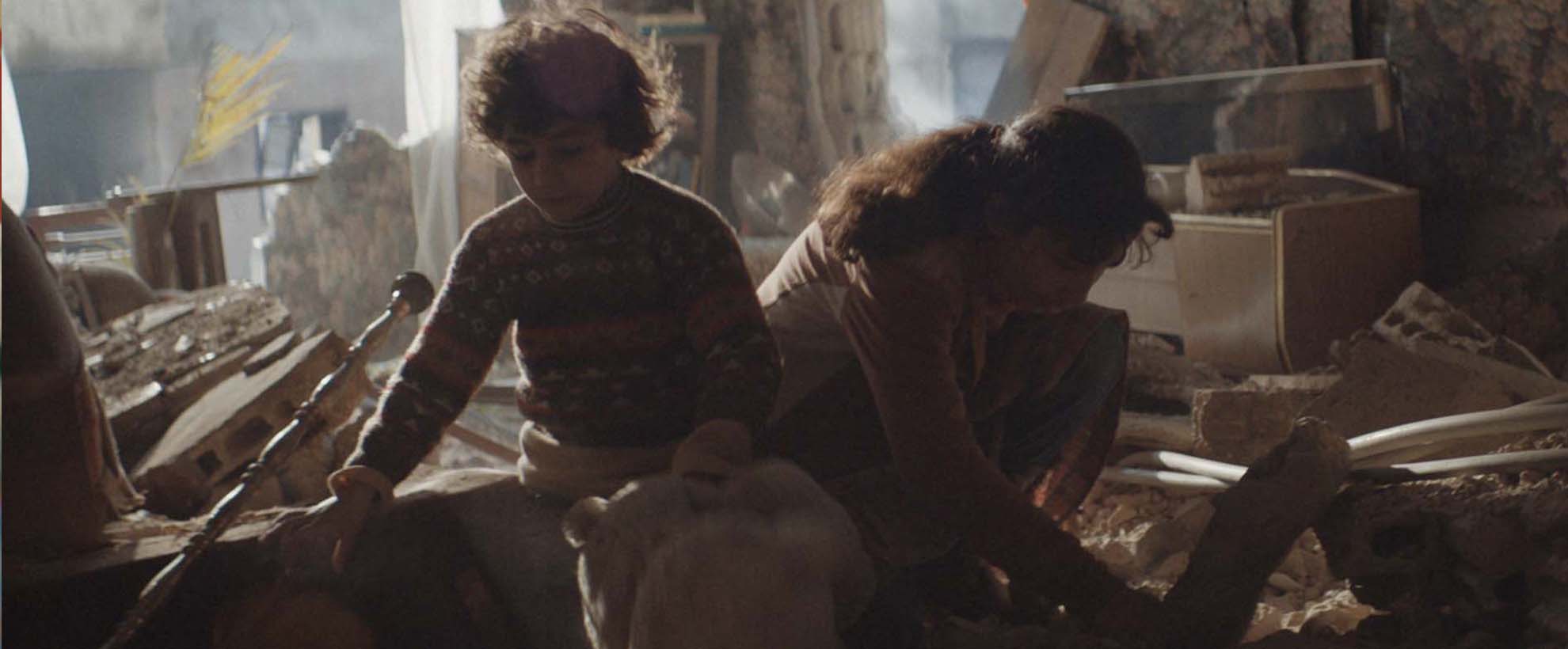Two young chilren, a boy and a girl, search through rubble