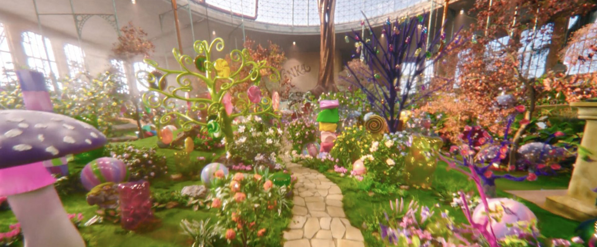 A fantastical room filled with creations from Willy Wonkas Chocolate Factory including trees and plants with sweets hanging from them and a chocolate tree.