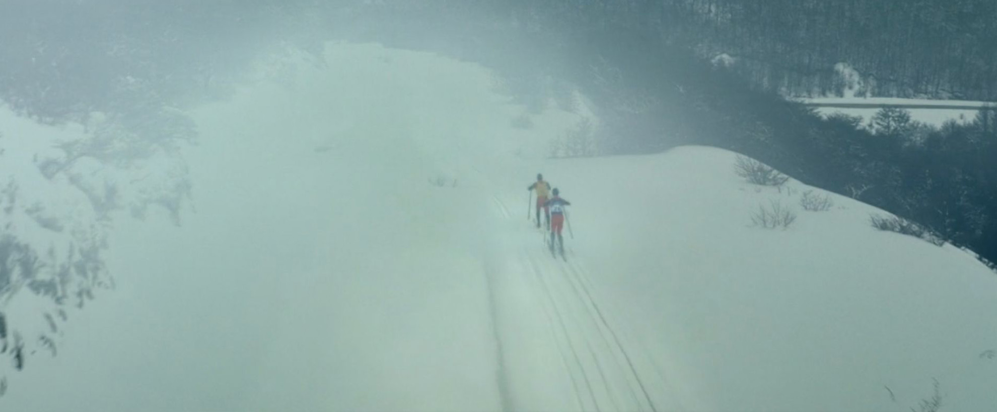 Two people cross country ski through the snow