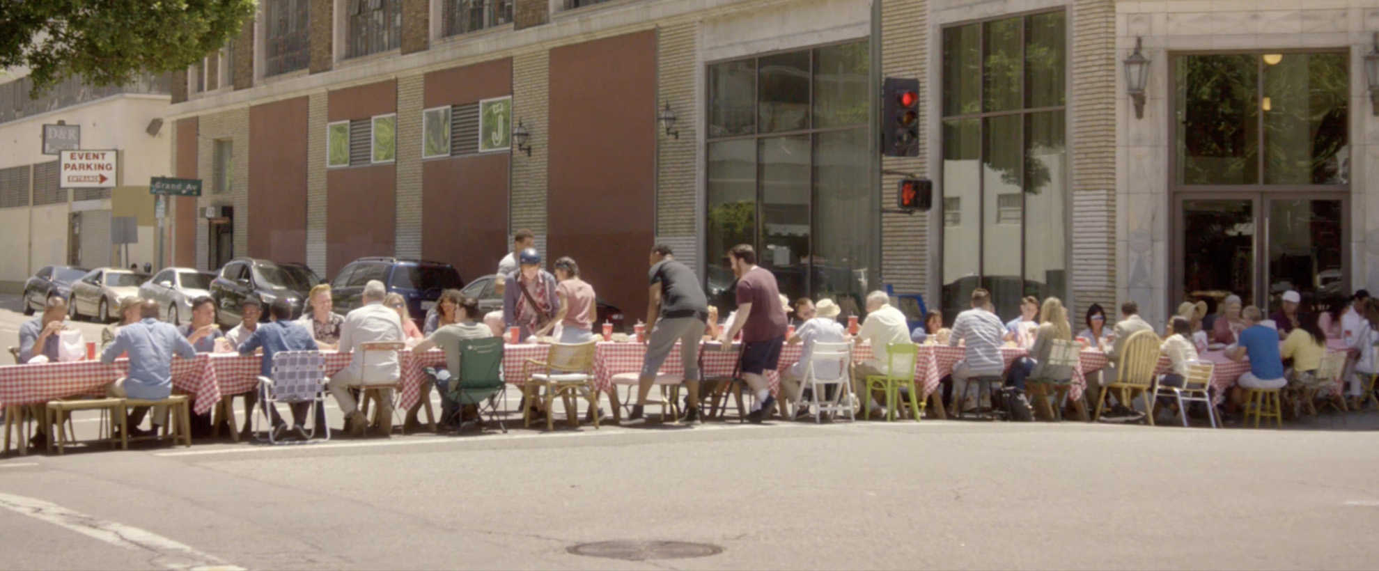 A group of people sit at a long table in the road at an intersection