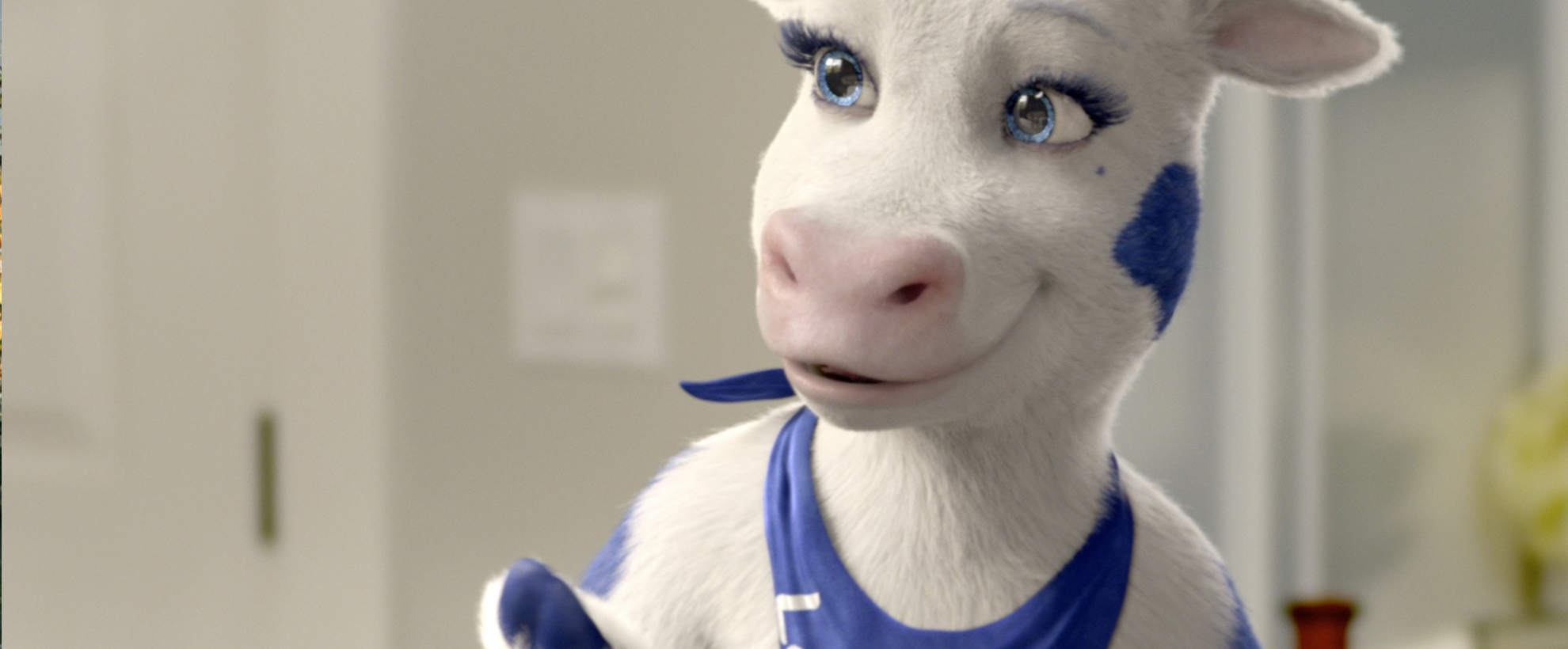 A white cow with blue spots and a blue bandana around her neck