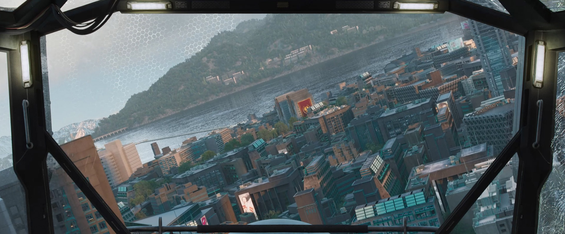 The view of a city block through a heads up display in a aircraft, there is a hill and a body of water in background.