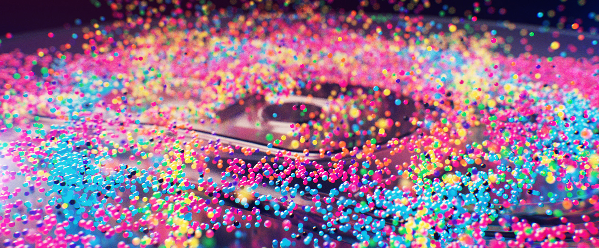 A speaker with multicoloured bubbles on it bouncing them up against a black background.