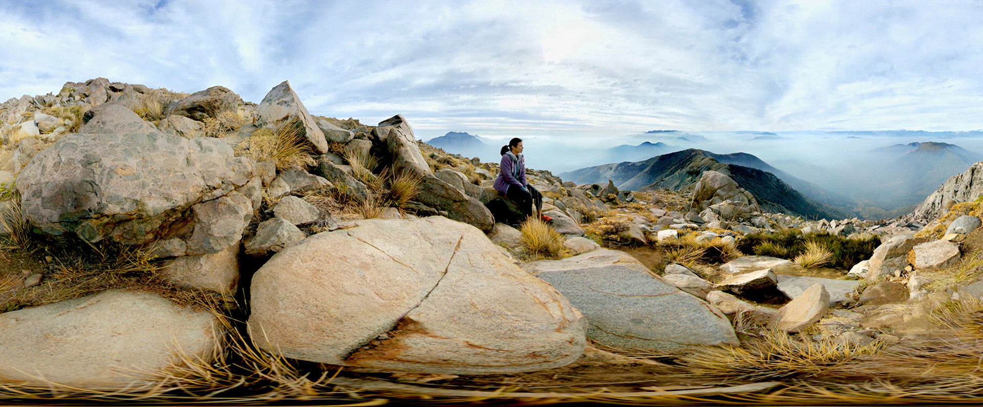 Lady sitting on rocks looking out to the distance