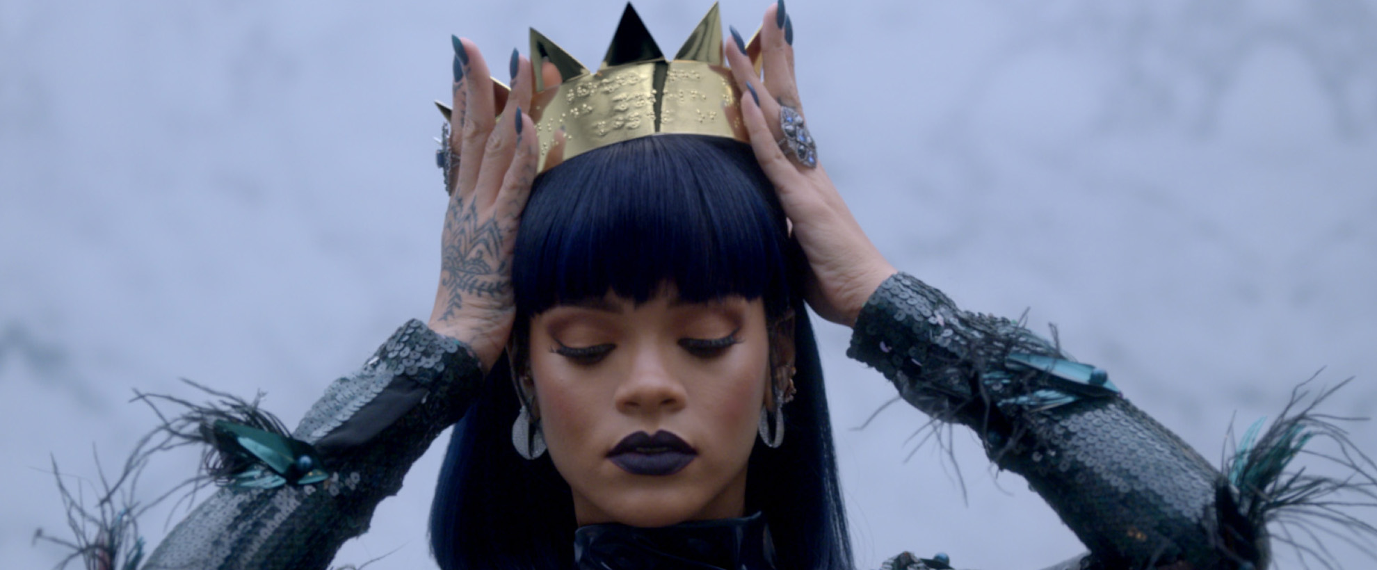 Rihanna puts a crown on her head and looks down