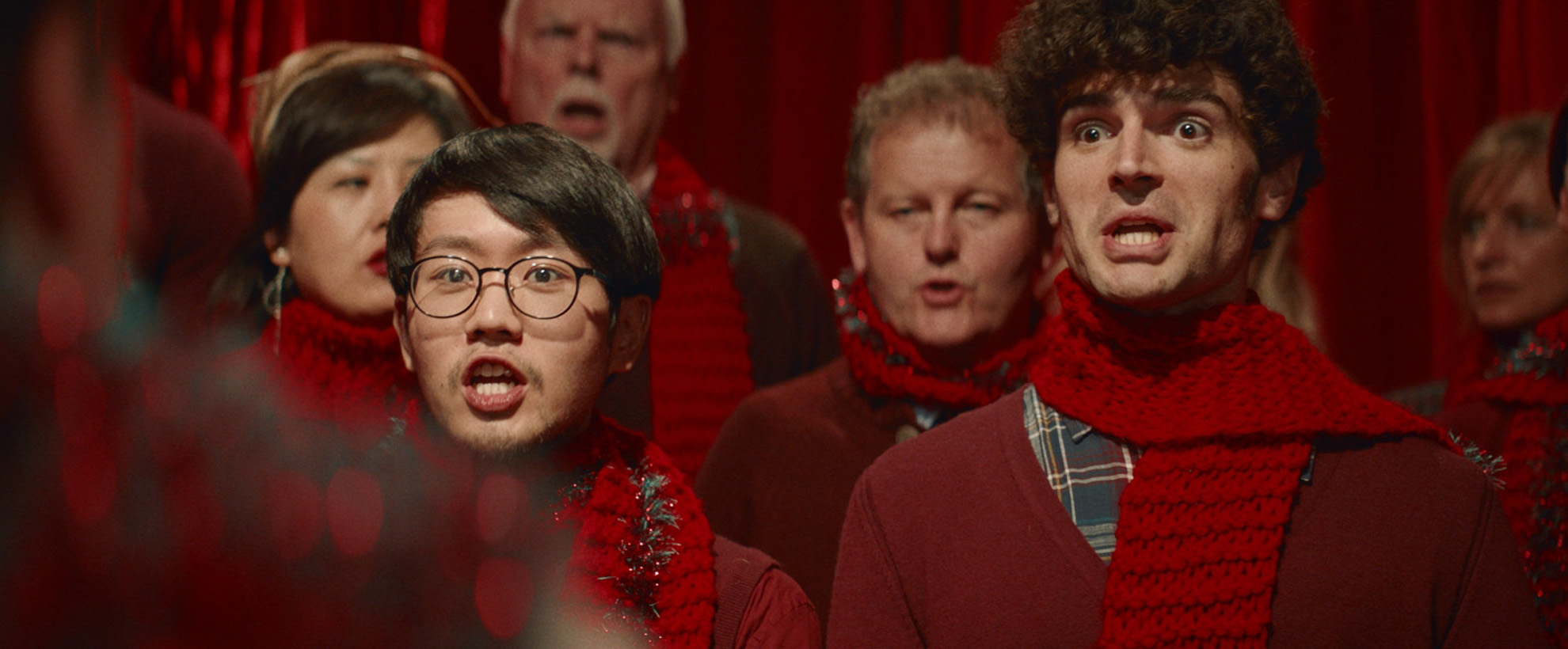Men in red sweats and red scarves singing