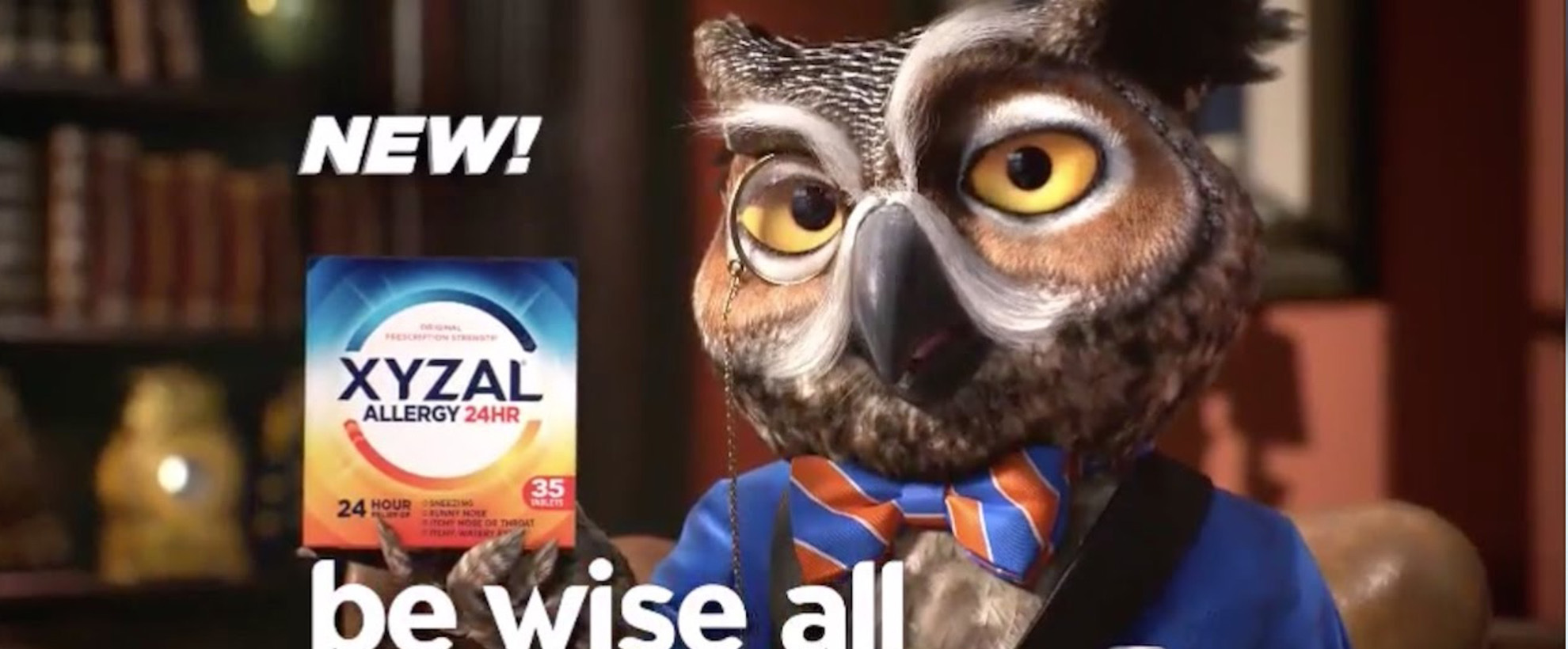 An animated owl with a monocle and a blue and orange striped bow tie holds up a box of XYZAL allergy medicine