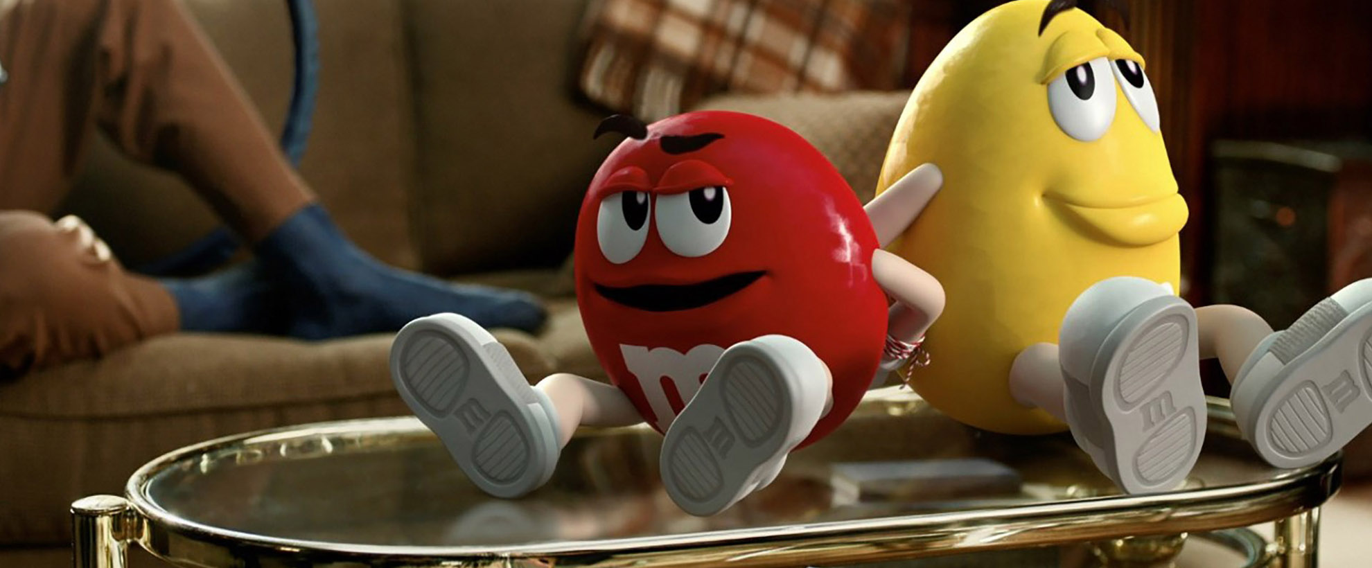 The red and yellow M&M mascots sit back to back with their hands tied