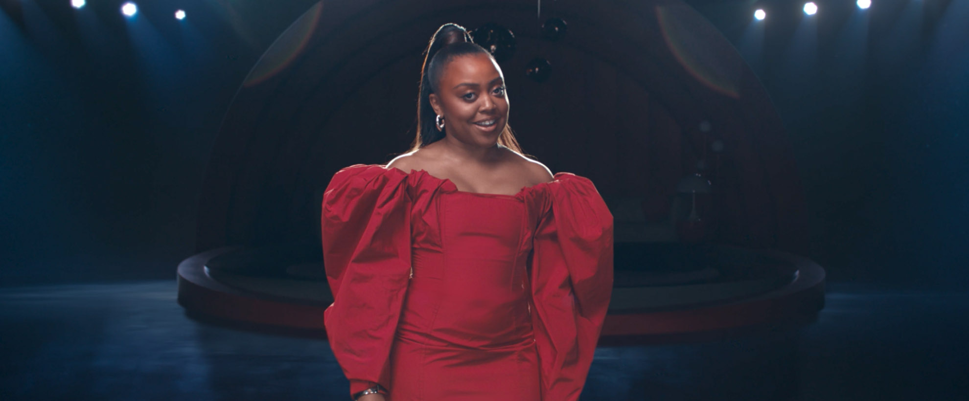 Quinta Brunson standing in a red dress