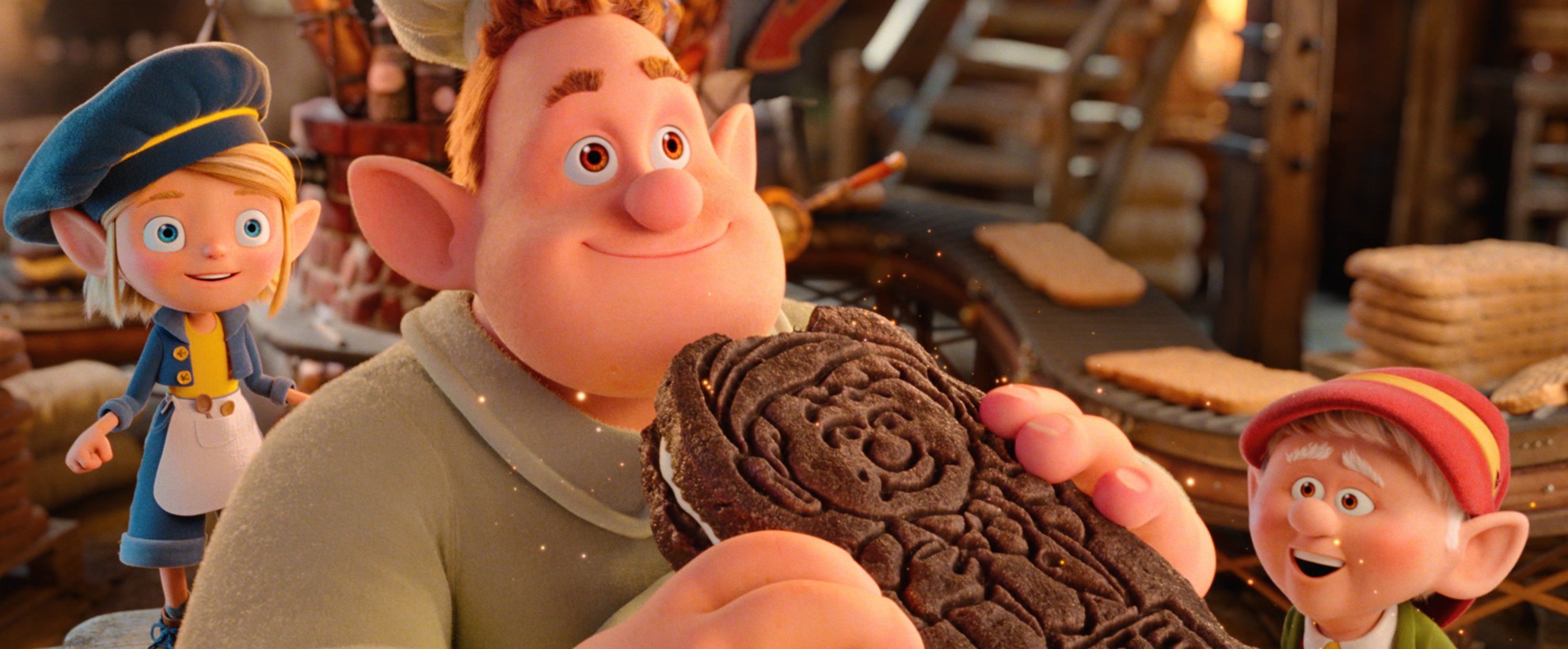 Three CG animated Keebler elves in the cookie factory. One eats a chocolate cookie