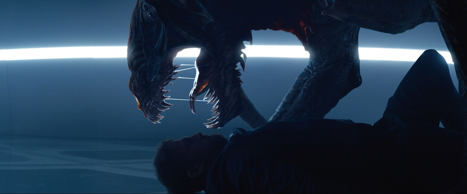 A CGI reptilian creature/monster holding a man down and opening its jaws