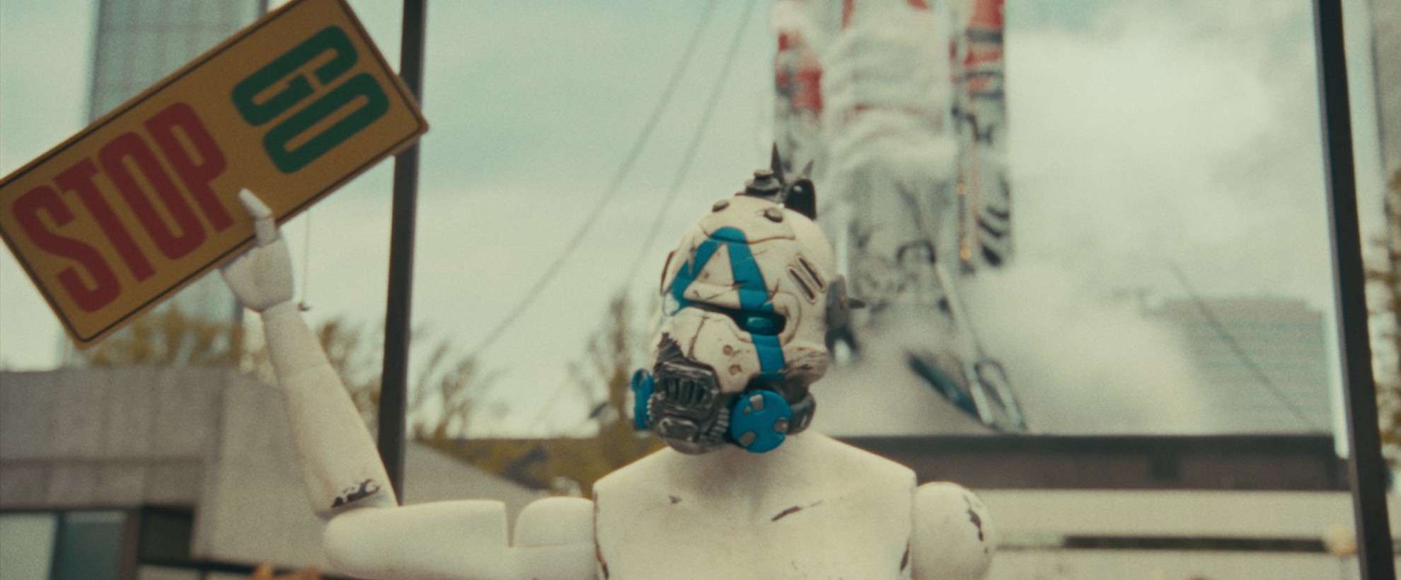 A white robot with a blue mask holds a sign that says "STOP GO"