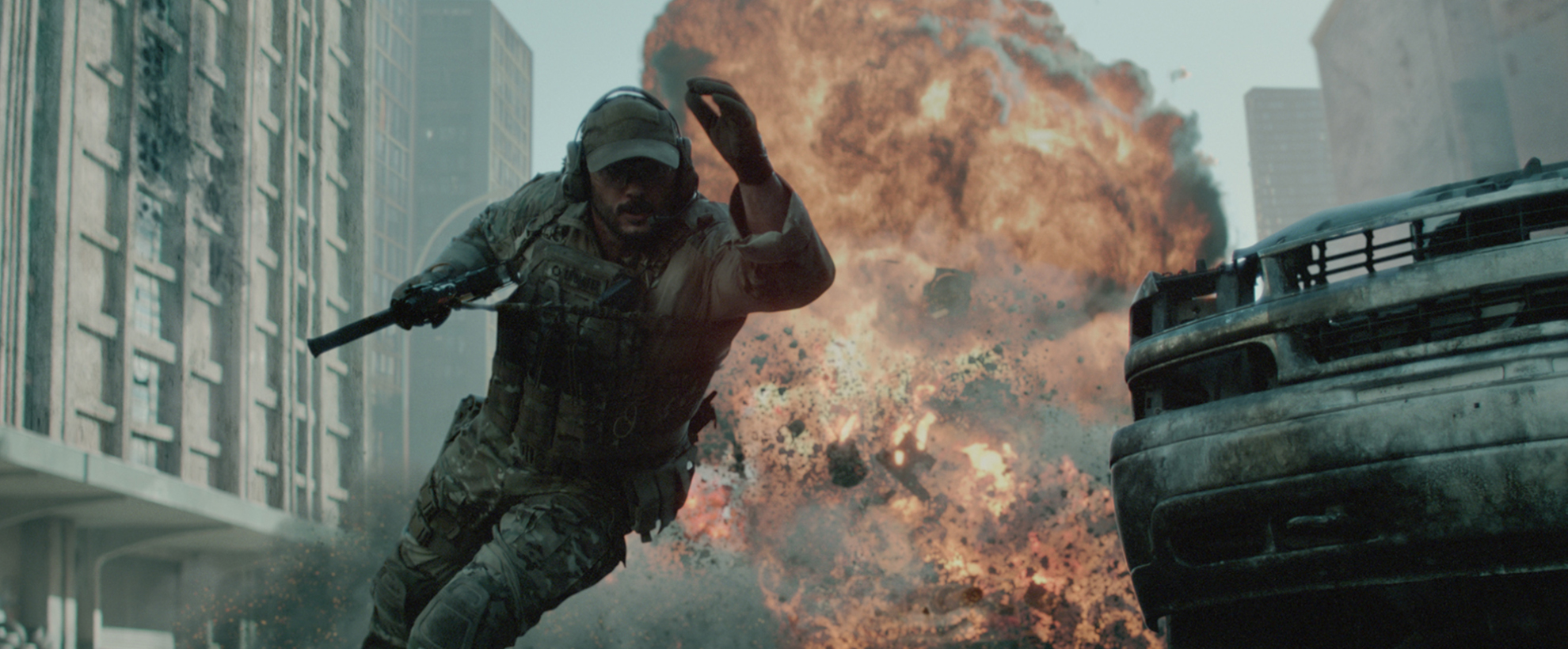 A soldier in tactical gear runs from a massive explosion in a city street, surrounded by debris and damaged vehicles.