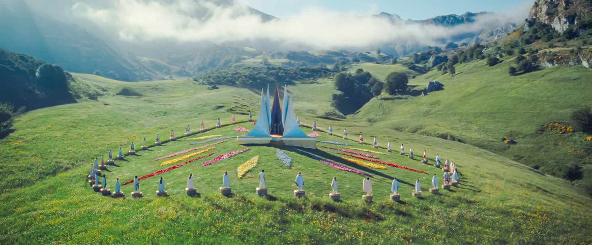 A CGI enhanced valley, with a central metal structure, surrounded by flowers