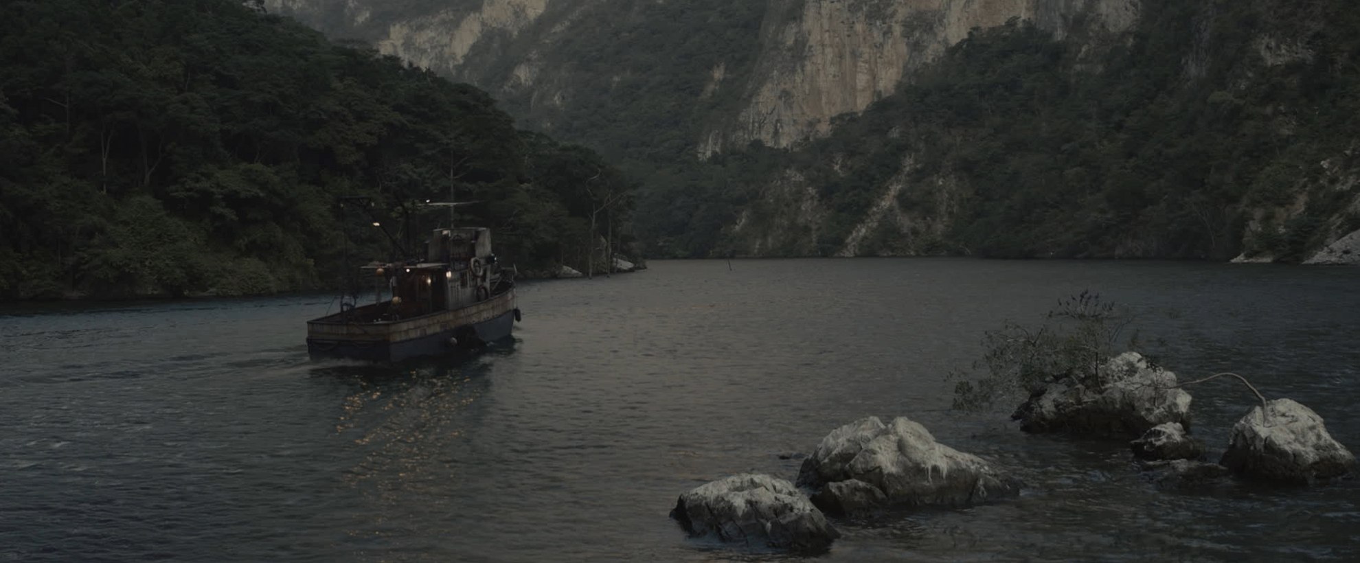 A small fishing boat on a lake towards a mountain