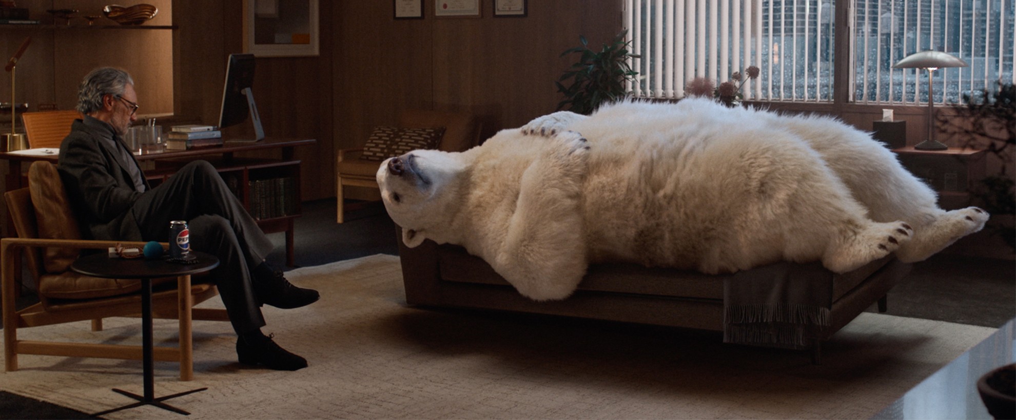 A CG animated polar bear lays on a therapists couch, his therapist (played by Taika Waititi) sits across sitting on a chair