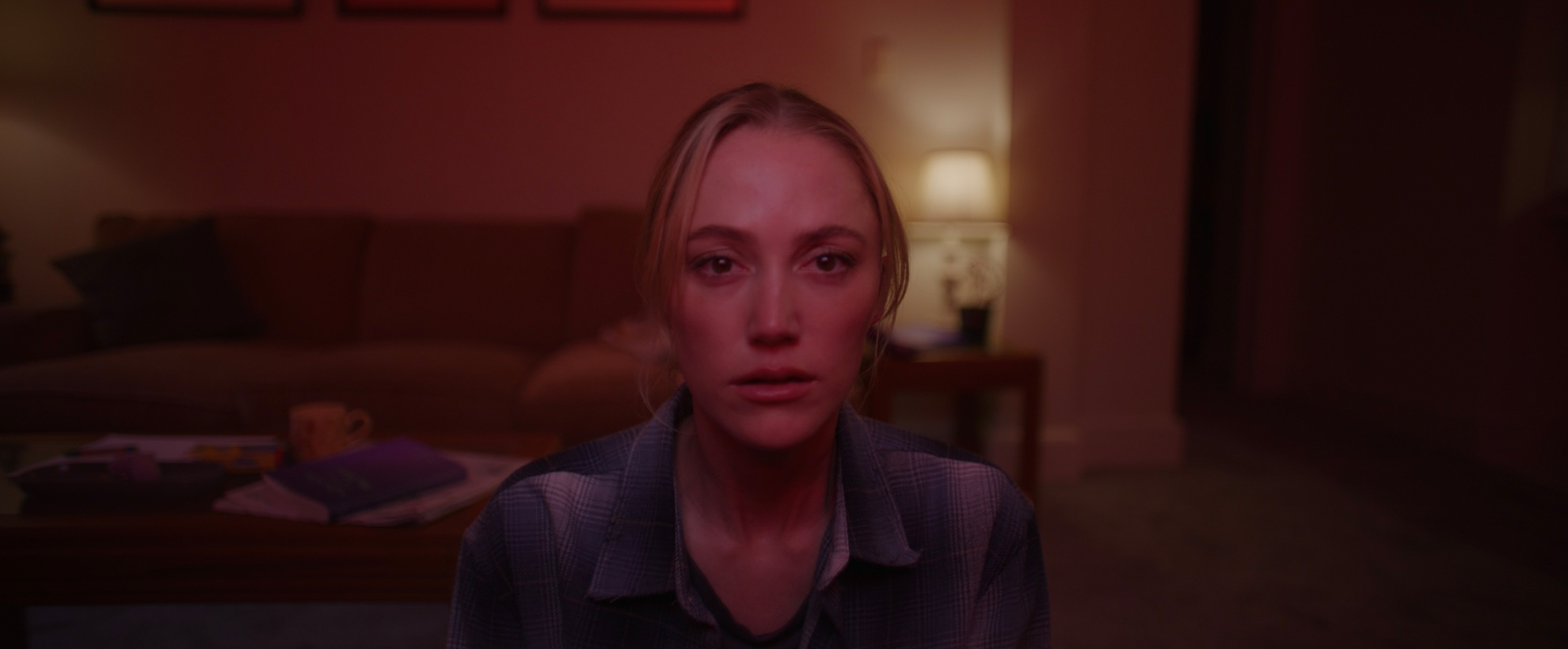 Actress Maika Monroe stares straight forward at a television in shock