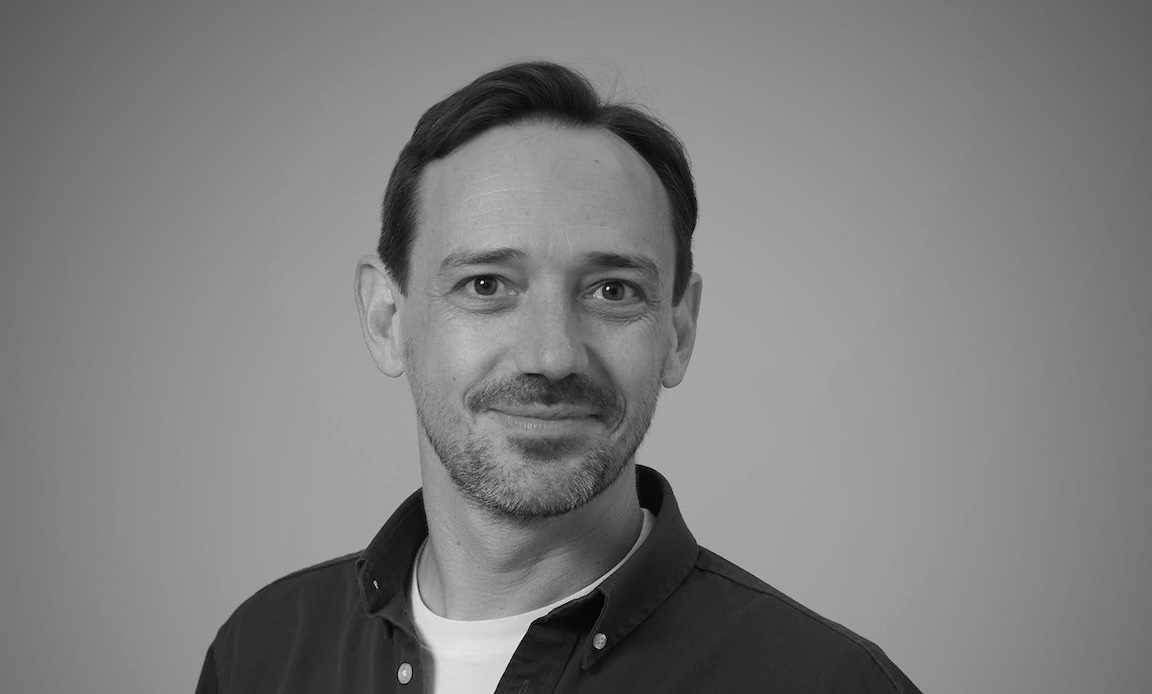 A black and white headshot of Dan Bethell