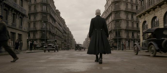 back shot of gellert grindelwald walking through 1920s paris