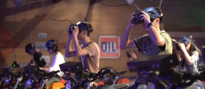side view of six people sitting on motorbikes putting on vr headsets