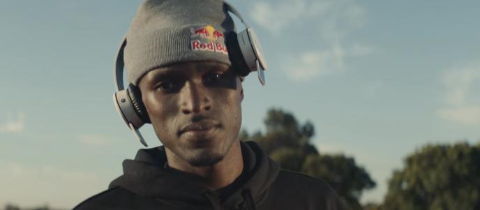 A young black man in a hoodie and beanie hat, with heaphones