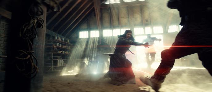 A woman fighting two men with glowing red swords, they are in a dust-filled dilapidated buidling.
