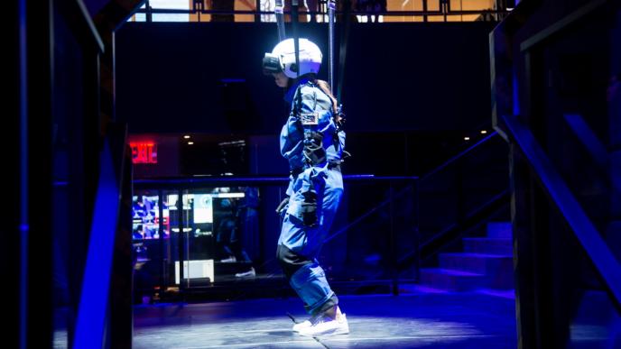 user wearing safety suit, helmet and VR headset preparing to be suspended in air through braces