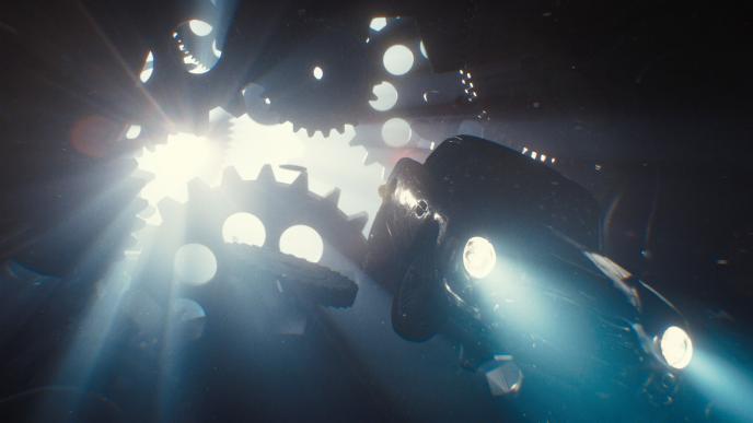 an animated car with its head lights on. it is in air. there are animated watch cogs in the background. light is peaking through the cogs