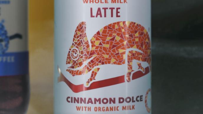 a can of whole milk latte with a graphic design chameleon on it. there is cinnamon dolce with organic milk text on the bottom