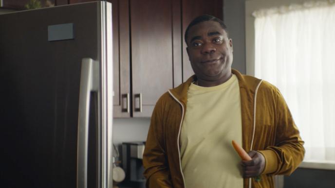 actor tracy morgan holding a carrot in front of a refrigerator