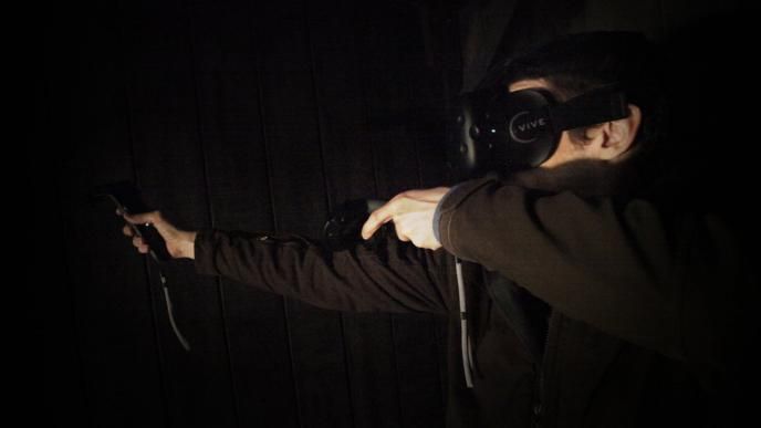 person wearing VR headset and holding VR controllers in an archery position
