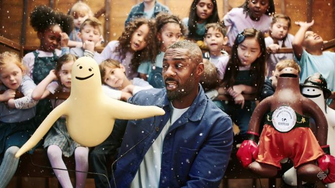 actor idris elba holding up a puppet in front of children