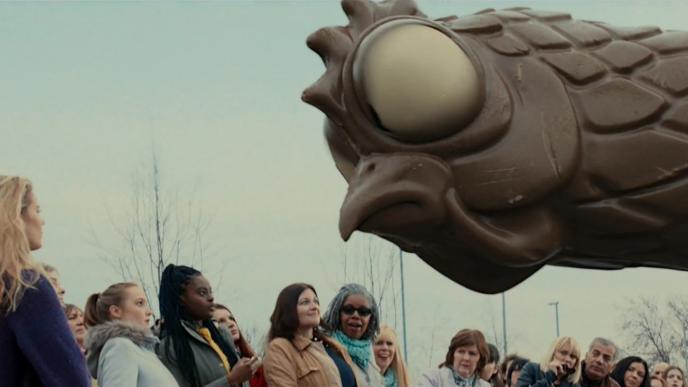 a giant chocolate hen looking at a crowd of stunned people